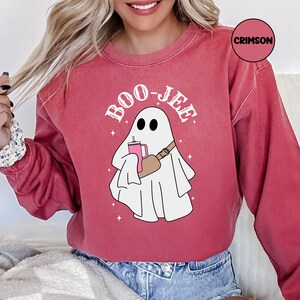May include: A red sweatshirt with a white ghost holding a pink drink and the text "BOO-JEE" in white.