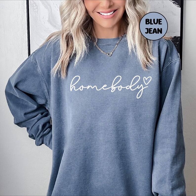 May include: A blue jean sweatshirt with the text "homebody" in white cursive lettering and a small white heart.
