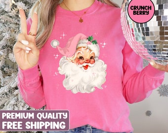 Könnte beinhalten: Rosa Langarm-Sweatshirt mit einer Vintage-Illustration von Weihnachtsmann auf der Vorderseite. Die Illustration zeigt einen rosa Hut, einen weißen Bart und eine rote Nase. Der Text "PREMIUM QUALITY FREE SHIPPING" befindet sich am unteren Rand des Bildes.