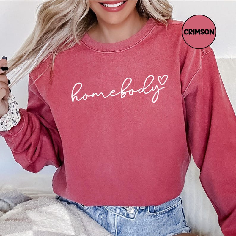 May include: A crimson red sweatshirt with the text "homebody" in white cursive lettering and a small white heart.