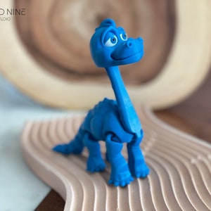 May include: A blue plastic toy dinosaur with articulated limbs. The dinosaur has a long neck and a friendly expression.