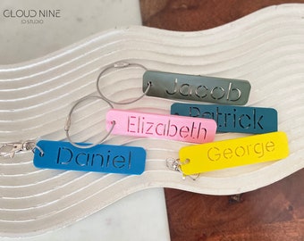 May include: Five colorful keychains with metal rings and cable chains. Each keychain has a different name cut out of the plastic: Jacob, Patrick, Elizabeth, Daniel, and George.