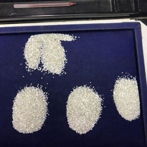 May include: Four piles of loose white diamonds on a blue velvet surface.