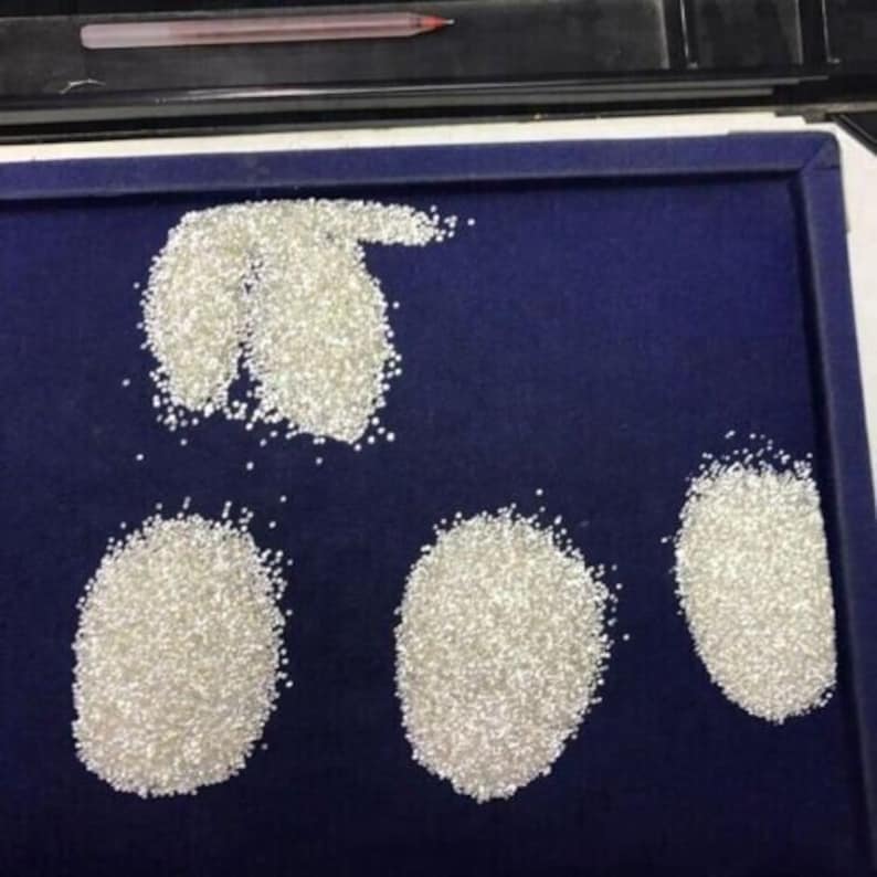 May include: Four piles of loose white diamonds on a blue velvet surface.