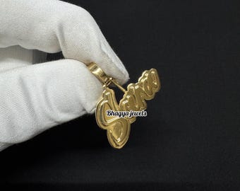 Puede incluir: Colgante de oro con el nombre "Jayda" en una fuente cursiva. El colgante está siendo sostenido por una mano que lleva un guante blanco.