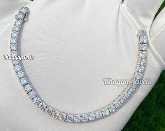 May include: A silver tennis chain bracelet with round clear cubic zirconia stones. The bracelet is on a white surface.  #bhagyajewels