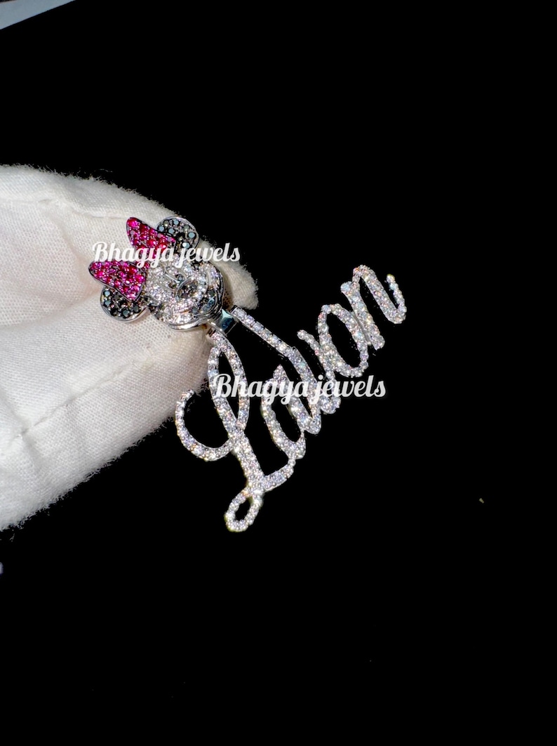 May include: A silver charm necklace with a sparkling diamond-encrusted name "Lavan" and a Mickey Mouse charm with pink and black accents.