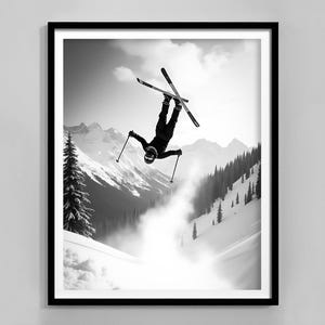 May include: A black and white photograph of a skier performing a backflip in the air while skiing down a snowy mountain slope.