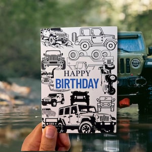 Könnte beinhalten: Eine weiße Geburtstagskarte mit schwarzen Illustrationen verschiedener Jeep-Modelle. Die Karte trägt den blauen Text "HAPPY BIRTHDAY". Im Hintergrund ist ein grünes Jeep-Modell zu sehen.