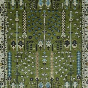 May include: A green rug with a floral pattern. The rug has a border with a white background and a green and blue floral design.