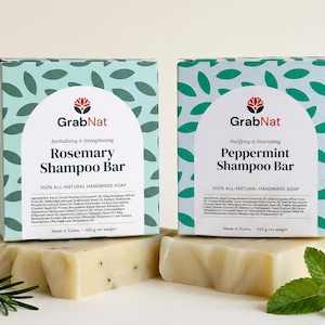 May include: Two rectangular boxes of GrabNat shampoo bars, one Rosemary and one Peppermint, featuring a light green leaf pattern. Each box displays the product name, ingredients list, and 100g net weight. Two solid shampoo bars sit in front.