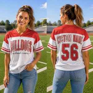 Könnte beinhalten: Ein weiß-rotes V-Ausschnitt-Trikot mit kurzen Ärmeln und gestreiften Bündchen. Die Vorderseite zeigt den Text BULLDOGS in einer roten Musterschrift mit school name darunter. Die Rückseite zeigt CUSTOM NAME und die Nummer 56 in roter Schrift.