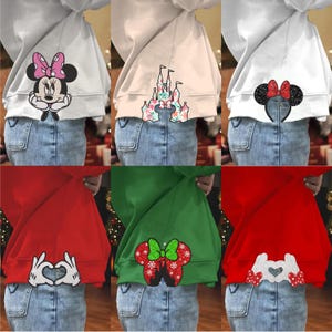 May include: Six different sweatshirts with various Disney character designs on the back. The sweatshirts are in white, pink, green, and red. The designs include Mickey Mouse, Minnie Mouse, a castle, and a heart.