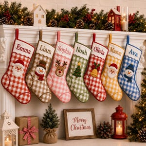 May include: Seven hanging Christmas stockings in a gingham check pattern, each embroidered with a name: Emma, Liam, Sophia, Noah, Olivia, Mason, and Ava. The stockings feature festive appliqués including Santa, a snowman, a reindeer, and a tree.