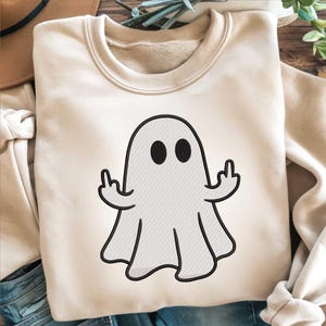 Puede incluir: Sudadera de color crema con un diseño de fantasma de dibujos animados. El fantasma tiene ojos negros y un contorno negro, y está mostrando el dedo medio con ambas manos. La sudadera tiene cuello redondo y mangas largas.