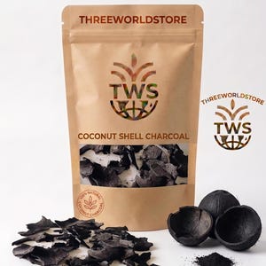 Peut inclure: Un sachet debout beige étiqueté THREEWORLDSTORE COCONUT SHELL CHARCOAL avec une fenêtre transparente montrant des morceaux de charbon noir. À côté du sachet se trouvent plusieurs fragments de coque de noix de coco et de la poudre.