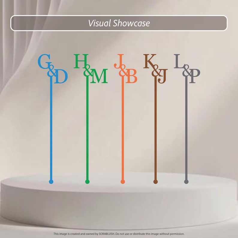 May include: Five thin, vertical cake toppers in blue, green, orange, brown, and gray. Each topper features a serif letter monogram with an ampersand, specifically G&D, H&M, J&B, K&J, and L&P. The text Visual Showcase appears at the top.