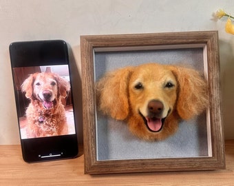 Puede incluir: Un retrato de un perro golden retriever hecho con fieltro de aguja enmarcado en un marco de madera marrón. El perro está sonriendo con la lengua afuera.