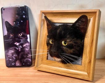Puede incluir: Retrato de gato enmarcado, hecho a mano, con apariencia realista. El gato tiene pelaje negro con marcas marrones y tostadas, ojos amarillos y largos bigotes blancos. Un smartphone muestra una imagen similar del gato. El marco es de madera clara.