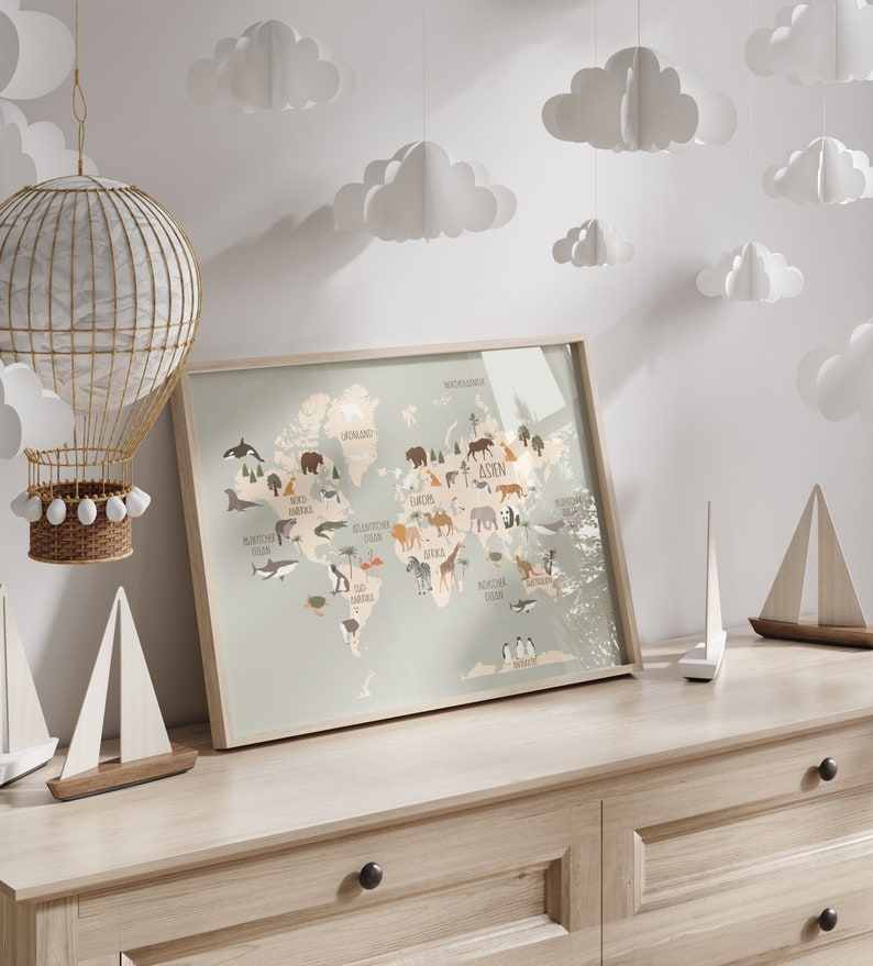 May include: A framed world map print with illustrations of animals from different continents. The map is on a light wood dresser with white paper clouds hanging from the ceiling.