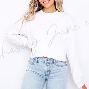 May include: A white long-sleeved top and light blue jeans. The top has a crew neck and a relaxed fit. The jeans are light wash denim with a classic five-pocket design. The text "Chasing June co" is written on the top.