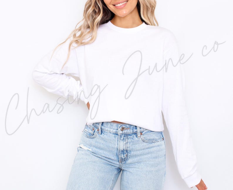 May include: A white long-sleeved top and light blue jeans. The top has a crew neck and a relaxed fit. The jeans are light wash denim with a classic five-pocket design. The text "Chasing June co" is written on the top.