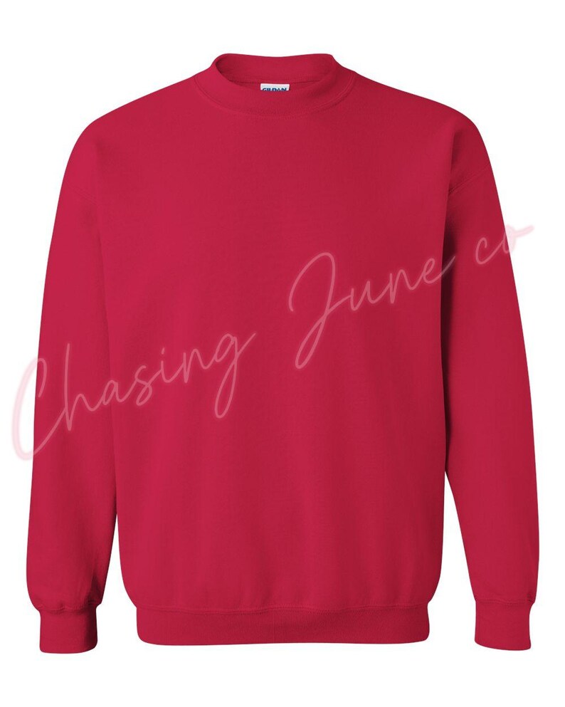 May include: A solid red crew neck sweatshirt. The long-sleeved top has a ribbed collar, cuffs, and hem. The text "Chasing June co" is written in a cursive font across the front of the sweatshirt.
