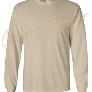 May include: A long-sleeved, beige-coloured shirt with a crew neck. The shirt is made of a soft material and has a classic, casual design. The brand name is visible on the collar.