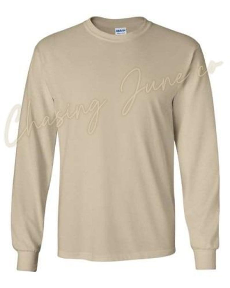 May include: A long-sleeved, beige-coloured shirt with a crew neck. The shirt is made of a soft material and has a classic, casual design. The brand name is visible on the collar.