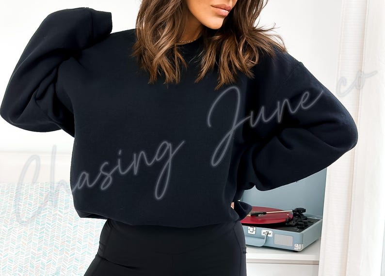 May include: A black sweatshirt with the text "Chasing June" in a cursive font. The sweatshirt is worn by a person. A record player is visible in the background.