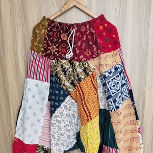 Könnte beinhalten: Bunte Patchwork-Haremshose mit verschiedenen Mustern, darunter Paisley und Streifen. Die Hose hat einen elastischen Bund mit Kordelzug und hängt an einem Holzbügel.