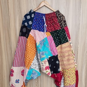 Könnte beinhalten: Patchworkhose in einer Vielzahl von Farben und Mustern, darunter Streifen, Blumenmuster und geometrische Designs. Die Hose hat einen Kordelzug in der Taille und Taschen. Der Stoff scheint leicht zu sein.