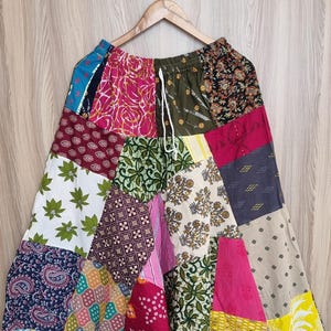 Könnte beinhalten: Bunte Patchwork-Hose mit Kordelzug in der Taille. Die Hose besteht aus verschiedenen Stoffen mit Mustern in Blau, Rosa, Grün, Gelb und Rot. Der lockere Schnitt ist ideal für Freizeitkleidung.