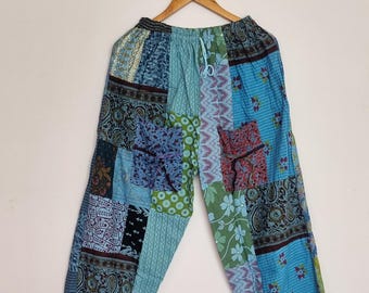 May include: Patchwork trousers featuring a variety of blue, green, and brown fabric panels with diverse patterns including paisley, floral, and geometric prints. These pants have an elastic waistband with a drawstring and two front pockets.