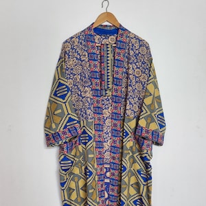 May include: A long-sleeved kimono-style robe featuring a patchwork design with blue, gold, and dark gray geometric patterns. The garment has a central vertical panel with a small red, blue, and white square motif and a floral print on the shoulders.