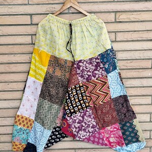 May include: Patchwork pants with a yellow, blue, pink, and green color scheme. The pants have a drawstring waist and a loose, flowing fit.