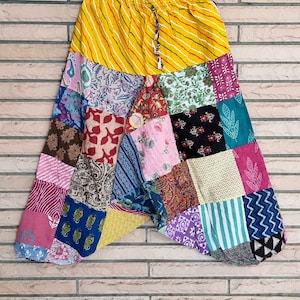 May include: Patchwork trousers with a yellow and white striped waistband. The trousers are made from a variety of colourful fabrics, including pink, blue, green and red.
