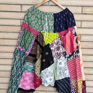 Puede incluir: Pantalones de patchwork con una variedad de patrones y telas coloridas. Los pantalones tienen una cintura con cordón y un ajuste holgado y fluido.