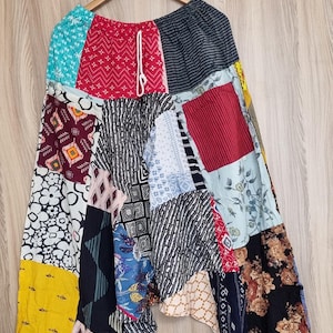 Könnte beinhalten: Patchwork-Hose mit einer Vielzahl von bunten Mustern, darunter florale, geometrische und gestreifte Designs. Die Hose hat einen Kordelzugbund und eine lockere, fließende Passform.