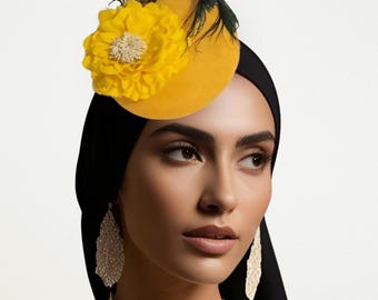 May include: A yellow hat with a large, yellow flower and black feathers. The hat is worn with a black head covering and paired with dangling, ornate earrings. The overall look is elegant and stylish.