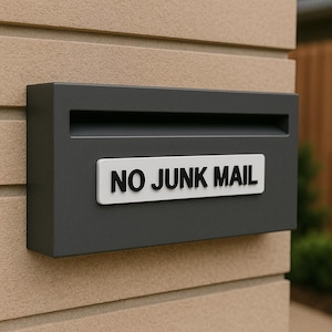 Peut inclure: Une boîte aux lettres en métal gris avec une pancarte blanche indiquant "NO JUNK MAIL".