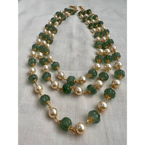 May include: A double-strand necklace with green and white beads. The beads are connected by gold-colored chain links.