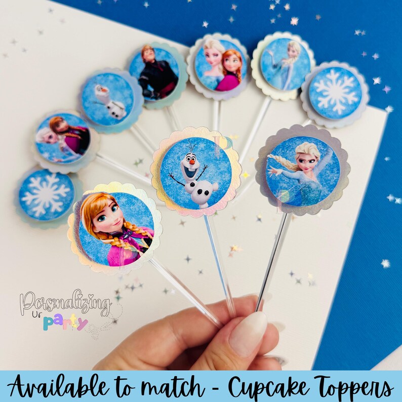 Peut inclure: Une collection de d&eacute;corations pour cupcakes rondes pr&eacute;sentant des images imprim&eacute;es de personnages du film La Reine des Neiges, dont Elsa, Anna et Olaf, ainsi que des flocons de neige. Chaque d&eacute;coration a un bord festonn&eacute; et une tige en plastique.