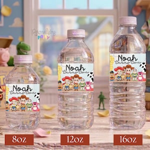 Puede incluir: Tres botellas de agua de pl&aacute;stico transparente con tapas de color rosa claro, cada una con una etiqueta personalizada con el texto 'Noah turns two' e ilustraciones de personajes de dibujos animados. Tama&ntilde;os de 8oz, 12oz y 16oz.