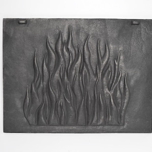 Peut inclure: Un écran de cheminée en fonte noire avec un motif en relief de flammes.