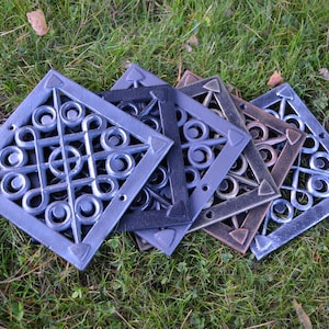 Può includere: Cinque griglie di ventilazione decorative in metallo a forma di diamante con un motivo a spirale. Le griglie sono in varie tonalità di grigio, nero, marrone e oro.