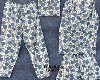 Può includere: Un completo pigiama coordinato con un motivo floreale blu e marrone su sfondo bianco. Il set include pantaloni, una camicia con bottoni, pantaloncini e un piccolo oggetto quadrato, il tutto appeso a un gancio.