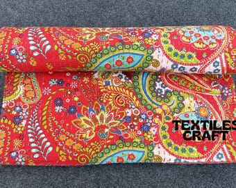 Könnte beinhalten: Rote Kantha-Steppdecke mit Paisley-Muster in Grün-, Blau- und Gelbtönen. Die Decke ist in der Mitte gefaltet und trägt ein Etikett mit der Aufschrift "TEXTILES CRAFT".