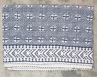 Könnte beinhalten: Eine weiße Baumwolldecke mit einem blauen geometrischen Muster. Die Decke hat einen Rand aus kleineren geometrischen Mustern.