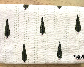 Puede incluir: Edredón blanco con un patrón repetido de árboles estilizados de color verde oscuro. Los árboles están espaciados uniformemente sobre la superficie. El edredón tiene una textura cosida con hilo verde. La esquina inferior derecha tiene el texto "TEXTILES CRAFT HANDMADE CREATIVITY".